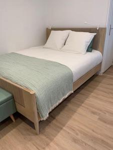 a bed with white pillows and a green blanket at Appartement chaleureux in Dijon