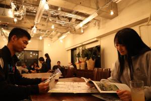 un hombre y una mujer sentados en una mesa mirando un mapa en Guest House Ichiyama Shukuba en Matsumoto