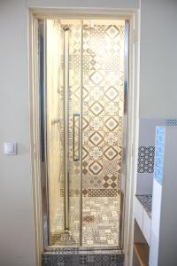 a shower with a glass door with a tile wall at CROIX BLANCHE - LE LOGIS in Tournan-en-Brie