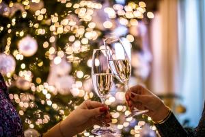 two people holding champagne glasses in front of a christmas tree at Hotel Excelsior - Liburnia in Lovran