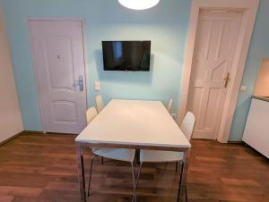 a white table and chairs in a room with a tv at Flora's House - Stylish, central one bedroom in Budapest