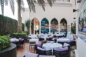 Al Gassar Resort في الدوحة: مطعم بالطاولات البيضاء والكراسي والنخيل
