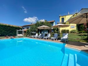 a large blue swimming pool with chairs and umbrellas at Residence delle Rose in Barolo