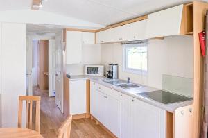 a kitchen with white cabinets and a sink and a window at KustCamp Gamleby in Gamleby