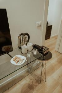 Four Luxury Suite في باليرمو: طاولة زجاجية مع غلاية الشاي وصحن من الكعك