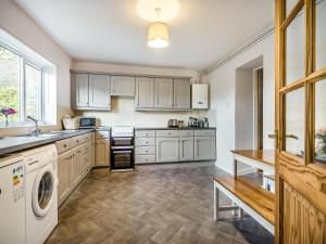 a kitchen with white cabinets and a washer and dryer at Harp Cottage in Brecon