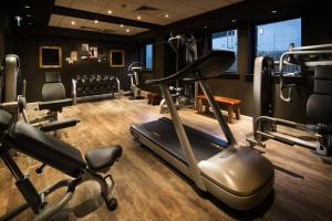 a gym with a treadmill and chairs in a room at pentahotel Liège in Liège