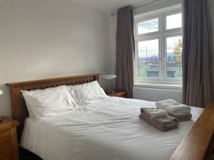 a bedroom with a bed with two towels and a window at Family friendly new flat at London Gants Hill Station near Ilford in Wanstead