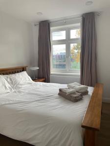 a bedroom with a white bed with a window at Family friendly new flat at London Gants Hill Station near Ilford in Wanstead