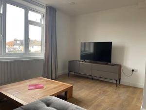 a living room with a flat screen tv and a table at Family friendly new flat at London Gants Hill Station near Ilford in Wanstead
