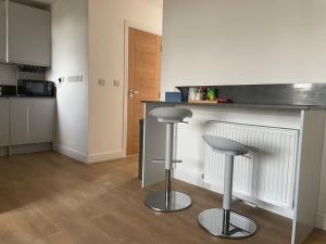 a kitchen with a counter and two stools at a bar at Family friendly new flat at London Gants Hill Station near Ilford in Wanstead