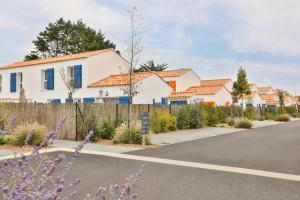una casa con una valla y flores púrpuras en Pierre & Vacances Premium Les Villas d'Olonne, en Les Sables-dʼOlonne