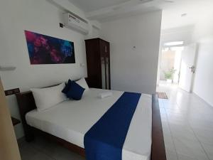 a bedroom with a bed with blue and white sheets at The Bamboo Tree Transit Hotel in Katunayake