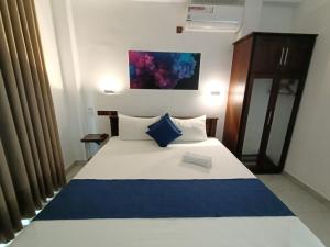 een slaapkamer met een bed met een blauwe en witte deken bij The Bamboo Tree Transit Hotel in Katunayaka