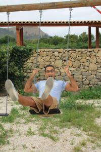 a man is sitting on a swing at Vecchia Dimora Resort in Centuripe
