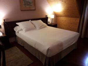 1 dormitorio con 1 cama grande con sábanas y almohadas blancas en Parador de Artíes en Arties