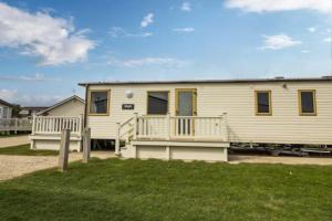 a large white house with a porch and a yard at Sunset Drive - Luxury caravan in Great Yarmouth