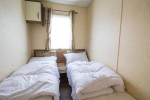 two beds in a small room with a window at Sunset Drive - Luxury caravan in Great Yarmouth