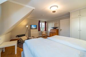 - une chambre avec un grand lit blanc et un bureau dans l'établissement Haus Syltzauber, à Keitum