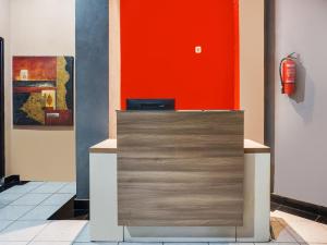 a reception desk with an orange wall and a fire extinguisher at OYO 3131 Sayang Home Stay in Makassar