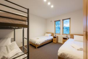 a bedroom with two bunk beds and two windows at RuPow Lodge - walking distance to Rusutsu Resort in Rusutsu