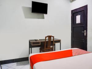 Habitación con cama, escritorio y TV. en OYO 3131 Sayang Home Stay en Makassar