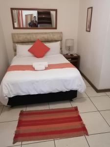 a bedroom with a large bed with a red pillow at Dove's Nest Guest House in Kempton Park