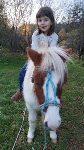 a little girl sitting on a miniature pony at Хотел Дончо Войвода in Koprivshtitsa