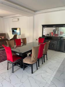 a dining room with a glass table and red chairs at Vilaria King mariot fully air conditioned villa فيلاريا كنج مريوط فيلا مكيفه بالكامل in Alexandria