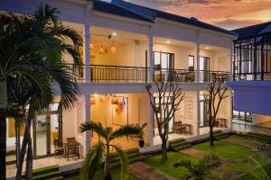 una grande casa bianca con palme di fronte di Tran Family Villas Boutique Hotel a Hoi An