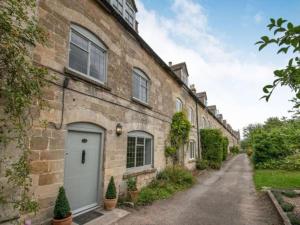 a brick house with a white door on a street at Park Cottage in Minchinhampton