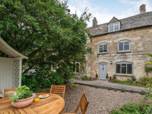 um quintal com uma mesa de madeira em frente a uma casa em Park Cottage em Minchinhampton