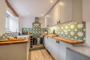 a kitchen with white cabinets and green and white stars on the wall at Park Cottage in Minchinhampton