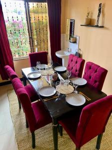 einen Esstisch mit lila Stühlen und einen Tisch mit Weingläsern in der Unterkunft Bungalow x Garten & Terrasse x WLAN x europäisch in Moshi