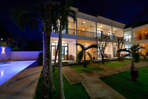 a house with a swimming pool and palm trees at night at Tran Family Villas Boutique Hotel in Hoi An