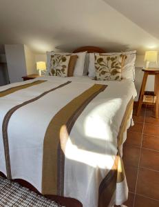 a bedroom with a large bed with white sheets and pillows at The Doll’s House in Tavira