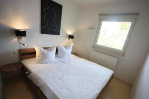 Un dormitorio con una cama con sábanas blancas y una ventana. en Windjammer, en Ostseebad Koserow