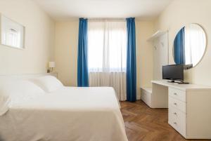 1 dormitorio con 1 cama y escritorio con TV en Residence Atlantico, en Lido di Jesolo