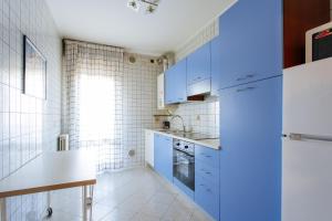 a kitchen with blue cabinets and a white tiled wall at Yourbanflat Sweet Home in Padova