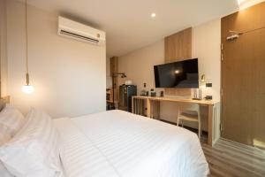 a bedroom with a bed and a desk with a television at SHAN Villas Sukhumvit in Bangkok