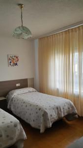 1 dormitorio con 2 camas y una ventana con cortinas en Casa Peña Sierra de Francia, en Aldeanueva de la Sierra