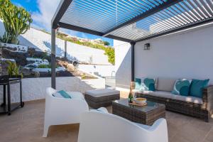un patio con muebles blancos y vistas al océano. en Villa Verode - Private Heated Saltwater Pool, en Tabaiba