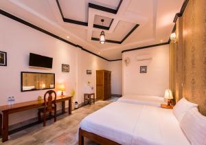 a bedroom with a bed and a desk and a tv at Sok San Villa in Battambang
