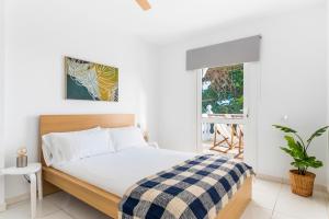 a white bedroom with a bed and a window at Villa Verode - Private Heated Saltwater Pool in Tabaiba