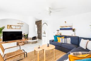 sala de estar con sofá azul y TV en Villa Verode - Private Heated Saltwater Pool, en Tabaiba