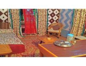 a room with two beds and a table and a chair at Blue heaven House boat, Srinagar in Srinagar