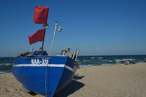 a blue boat sitting on a beach with flags at Villa Wauzi in Baabe