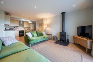 a living room with a green couch and a television at Lily Cottage in Little Walsingham