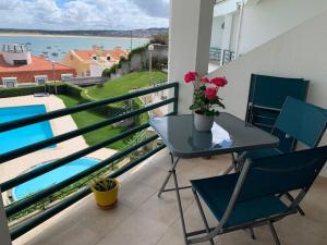 a balcony with a table and chairs and a view of the water at Casa na onda Sonho da Baia in São Martinho do Porto