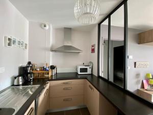 una cucina con piano di lavoro nero e forno a microonde di Superbe appartement terrasse, proche de la plage a Bénodet